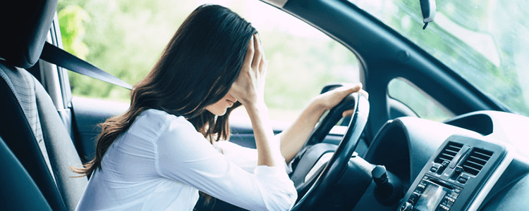 車内で頭を抱える女性のイメージ