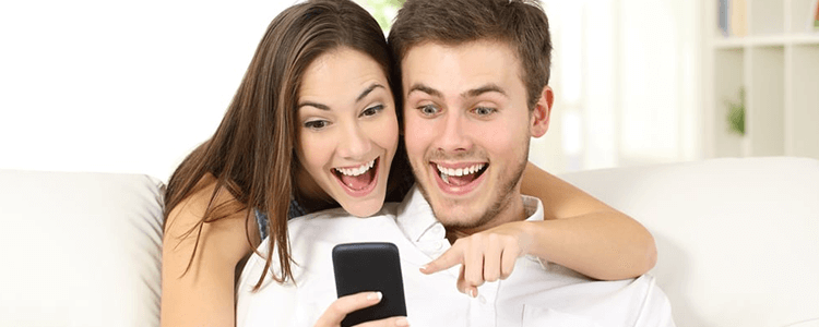 スマホの画面を見ながら笑うカップルのイメージ