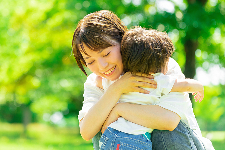 新緑の中で息子を抱き寄せる母親