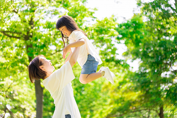 新緑の中で娘を抱きかかえる母親